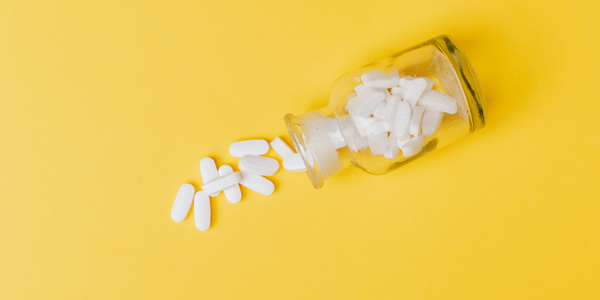bottle of pills spilling onto a yellow background